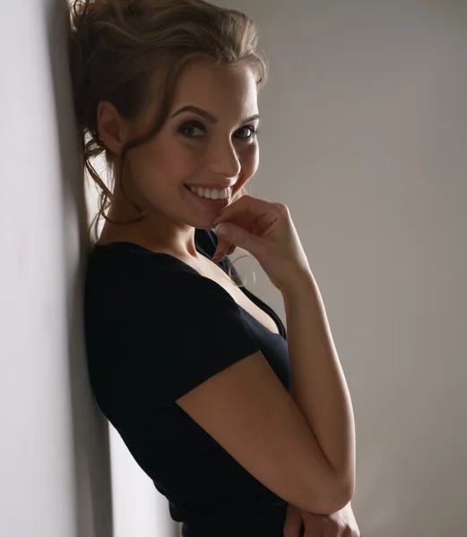 Härlig brunett i svart klänning ler mot kameran — Stockfoto