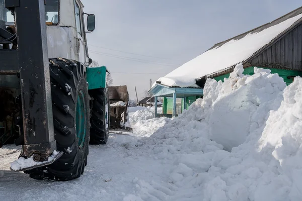 Hora de invierno. El tractor limpia la nieve en la aldea —  Fotos de Stock