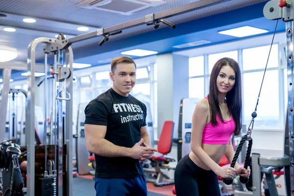 En el gimnasio. Instructor de fitness ayudando a mujer bonita — Foto de Stock