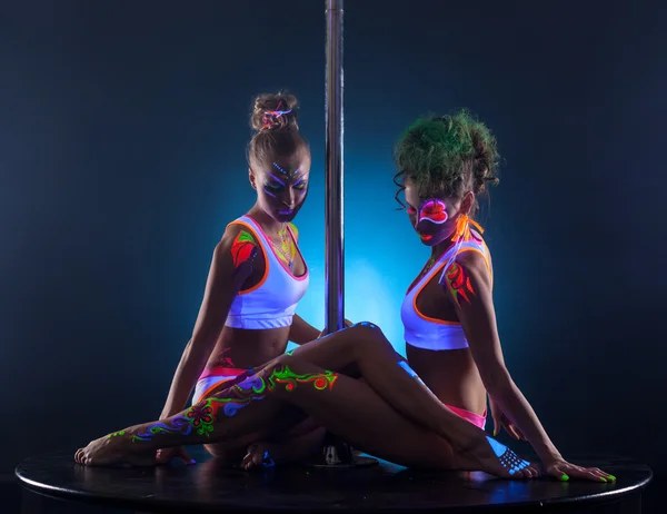 Sexy female dancers sitting together near pole — Stock Photo, Image