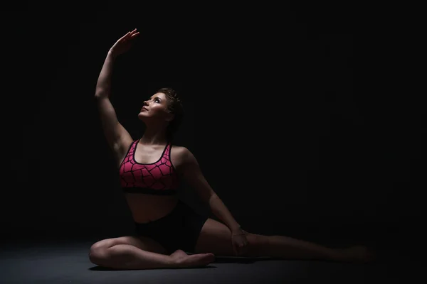 Estudio foto de la mujer elegante ejercitándose en la oscuridad —  Fotos de Stock