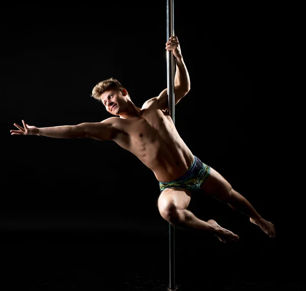 Smiling guy posing while performing trick on pole — Stock Photo, Image