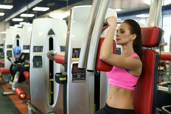 Beautiful young woman exercising on simulator — Stock Photo, Image