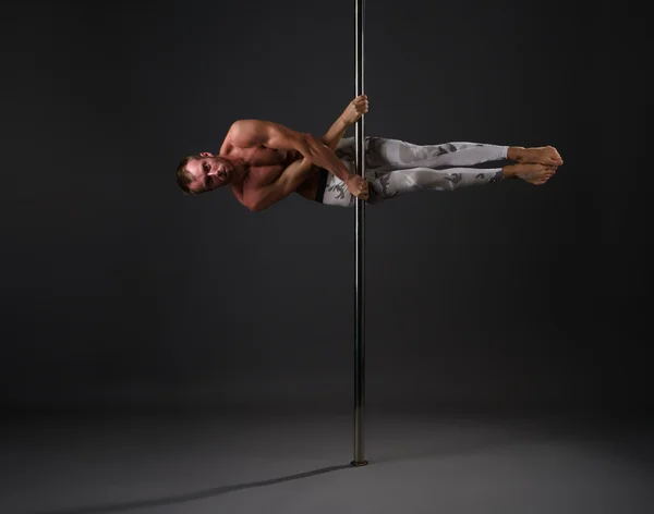 Studio immagine di ballerino di sesso maschile che esercita sul palo — Foto Stock