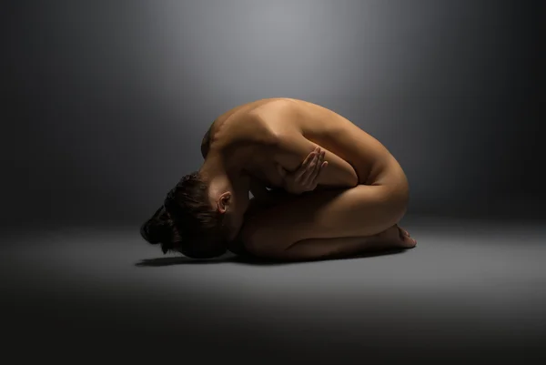 Naked woman lying on floor, hugging herself — Stock Photo, Image