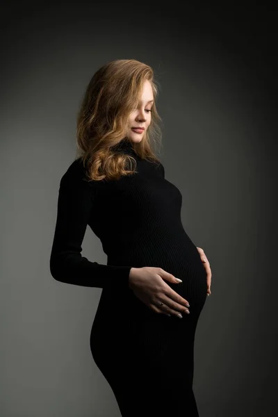Mujer embarazada en vestido negro en el estudio — Foto de Stock