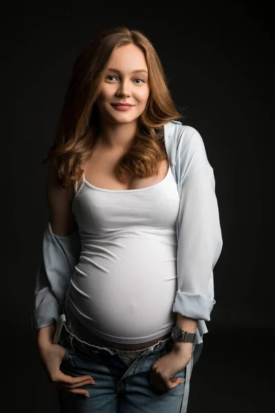 Junge schwangere Frau in lässiger Kleidung im Studio — Stockfoto