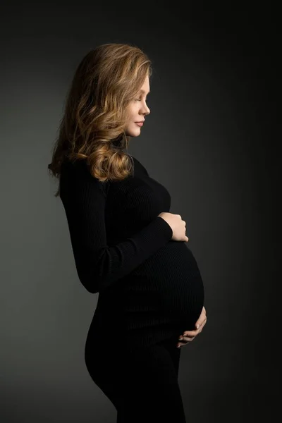 Stüdyoda siyah elbiseli hamile kadın. — Stok fotoğraf