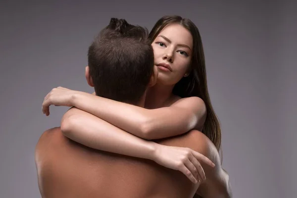 Frau umarmt hemdlosen Freund und blickt in Kamera — Stockfoto