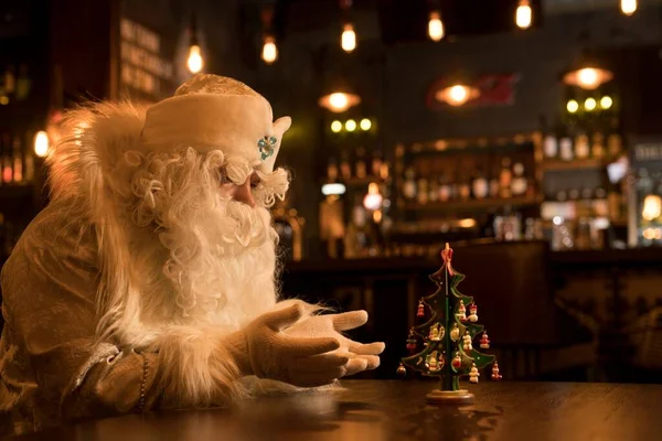 Pensativo Santa Claus rezar por pequeño árbol de Navidad — Foto de Stock