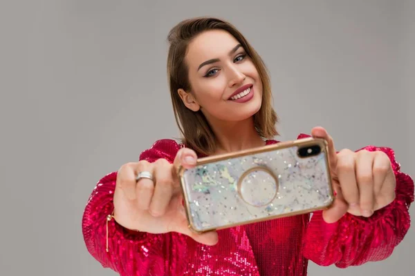 Счастливая молодая женщина показывает блестящий мобильный телефон — стоковое фото