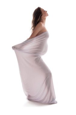 Stüdyoda beyaz giysili çıplak hamile kadın.