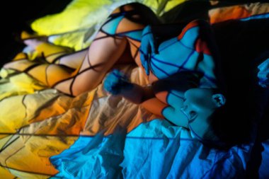 Karanlık odada projektör ışığının altında yatan kadın.