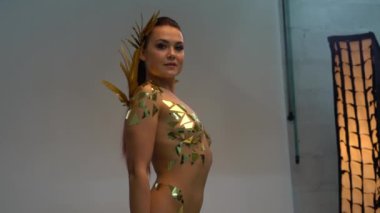 Altın kanatlı ve sahne arkasında kostüm giyen bir model.