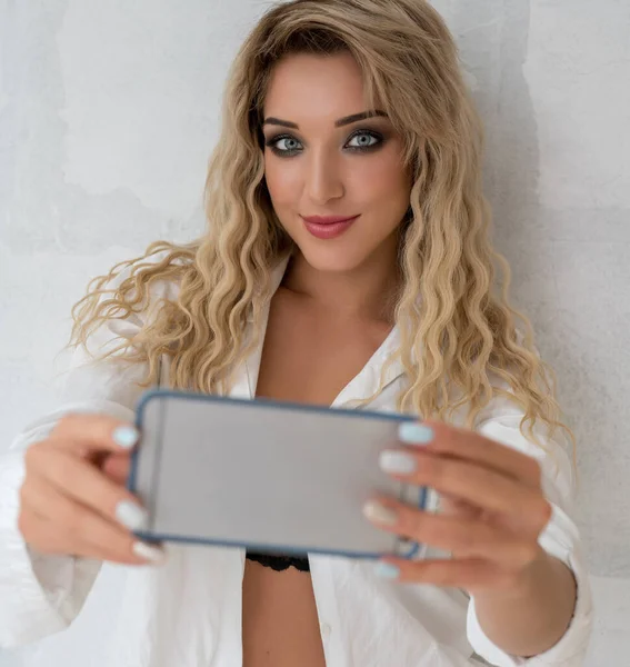 Сексуальная блондинка делает селфи на камеру в студии — стоковое фото