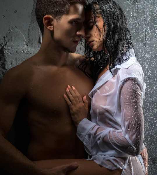 Sensual young wet couple hugging under rain