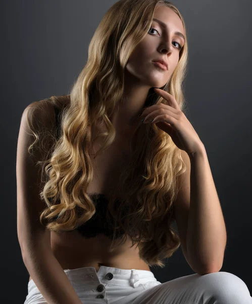 Sexy blondýna na kostce v bílé hubené džíny a podprsenka — Stock fotografie