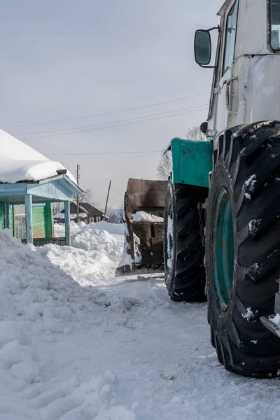 Hora de invierno. El tractor limpia la nieve en la aldea —  Fotos de Stock