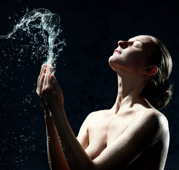 Giovane ragazza in topless prendere spruzzi d'acqua sul viso al buio — Foto Stock