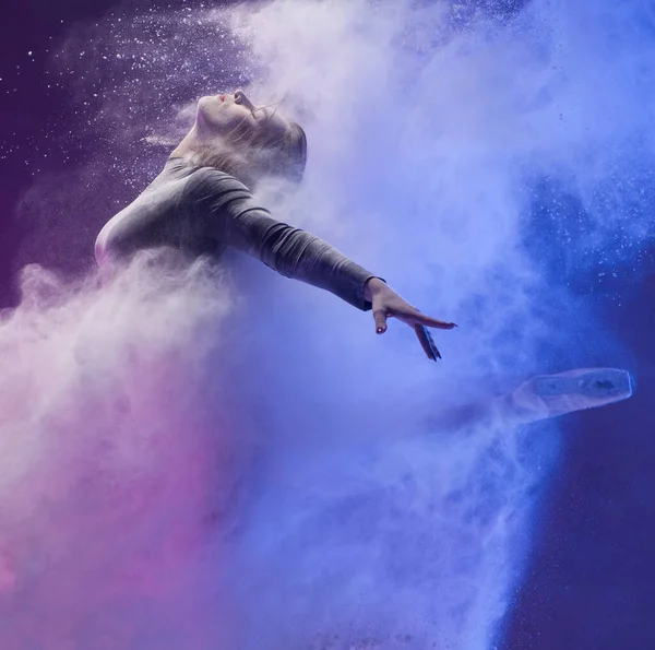Девушка в пуантах в облаке пыли и цветном свете — стоковое фото