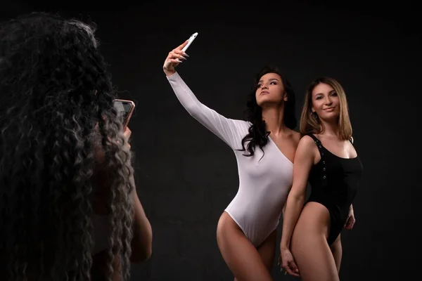 Attractive diverse women in studio taking selfie smartphone — 图库照片