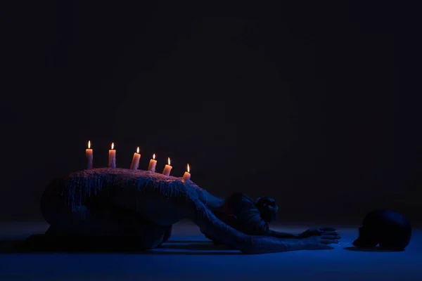 Анонимная женщина с горящими свечами в темноте — стоковое фото