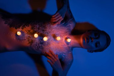 Vücudunda mumlar yanan kadın model.