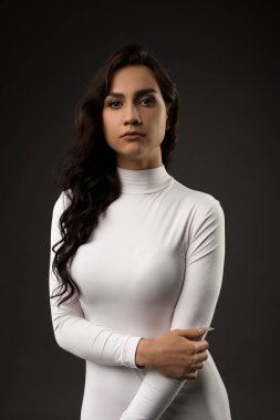 Beyaz elbiseli çekici bir kadın kameraya bakıyor.