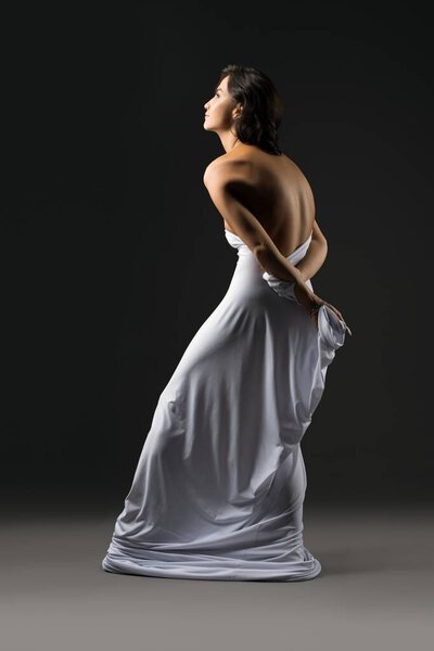 Slim graceful woman wrapped in white cloth in studio