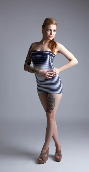 Sexy tätowierte Frau posiert auf grauem Hintergrund — Stockfoto