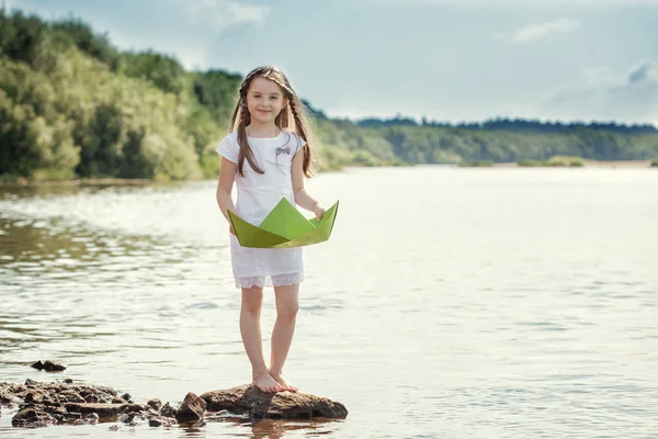 Очаровательная девушка позирует с бумажной лодкой на озере — стоковое фото