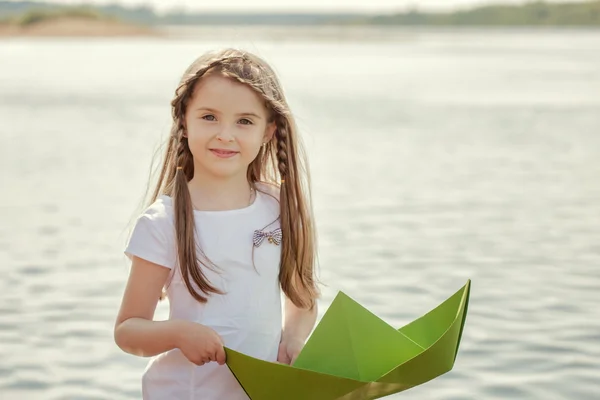 Dolce bambina in posa con barca di carta, primo piano — Foto Stock