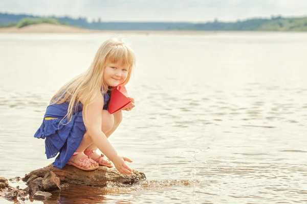 Prise de vue de joyeux fille veut courir bateau en papier dans le lac — Photo