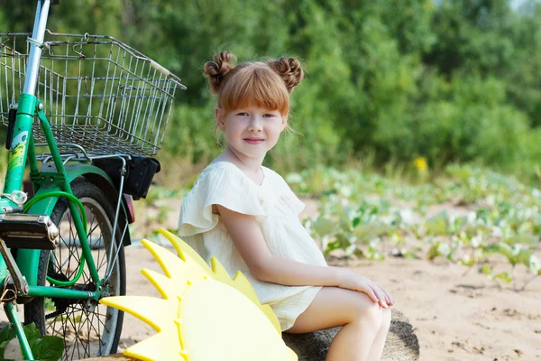 Legrační zrzavá holčička pózuje s kol — Stock fotografie