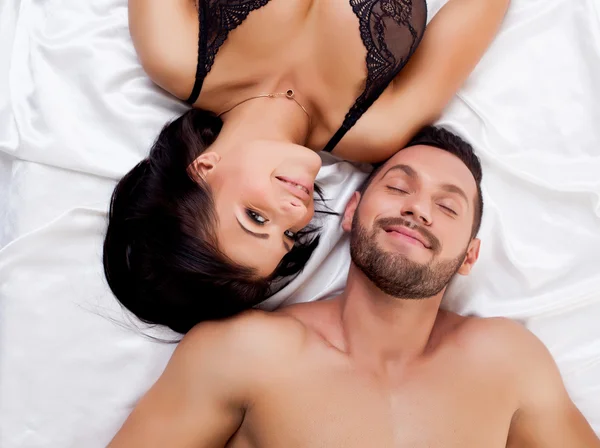 Attractive sexual partners lying on satin sheets — Stock Photo, Image