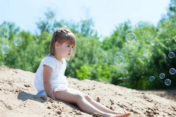 Verrast meisje kijkend naar zeepbellen in park — Stockfoto