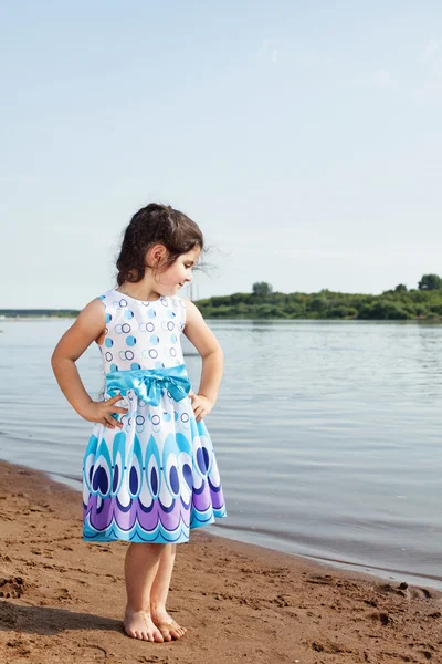 Kleines Mädchen posiert in schickem Kleid vor Seekulisse — Stockfoto