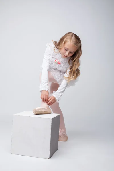 Kudrnatá holčička vázání pointe, na šedé pozadí — Stock fotografie