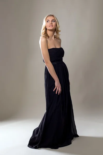 Lächelnde hübsche Blondine posiert im langen schwarzen Kleid — Stockfoto