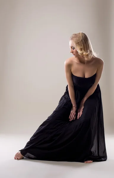 Attraktive Blondine im schwarzen Kleid posiert vor der Kamera — Stockfoto