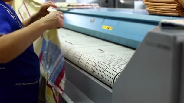 Рабочий загружает простыню в гладильную машину — стоковое видео