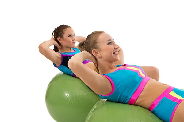 Smiling girls pump abdominals on fitness balls — Stock Photo, Image