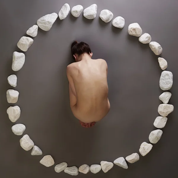 Fille nue couchée en cercle de pierres. Vue du dessus — Photo