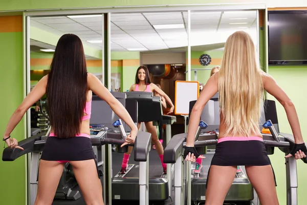 Visão traseira de meninas esportivas se exercitando em esteiras — Fotografia de Stock
