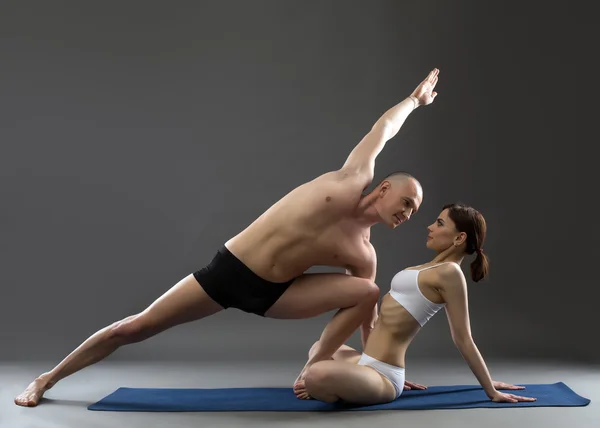 Studio shot van gepaarde yoga, op grijze achtergrond — Stockfoto