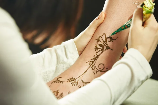 Art of mehndi. Master paints models leg — Stock Photo, Image