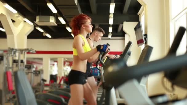 Les jeunes faisant de l'exercice sur des tapis roulants en salle de gym — Video