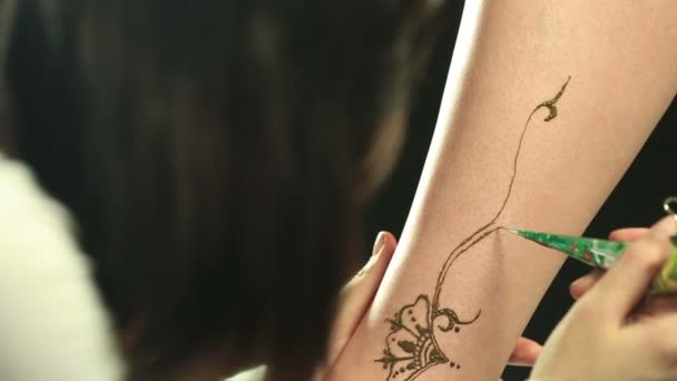 Master disegna su gamba del modello utilizzando hennè, primo piano — Video Stock