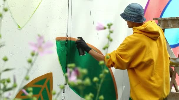 Творческий парень рисует картину на стене в парке — стоковое видео