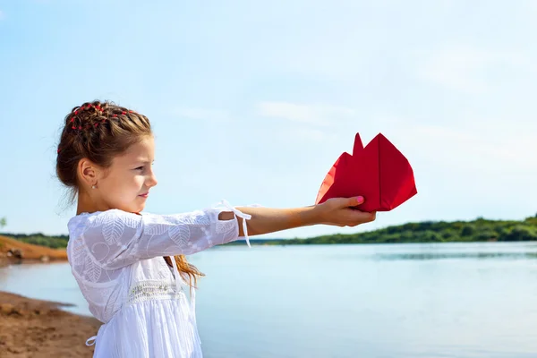 Adorabile bambina con in mano una barca di carta rossa — Foto Stock